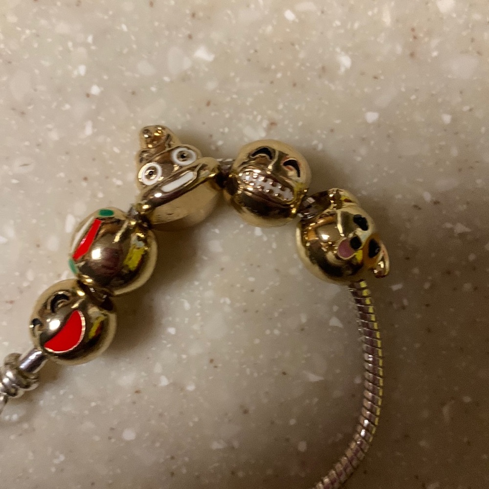 Silver colored bracelet with gold colored emojis beads lobster clasp with heart